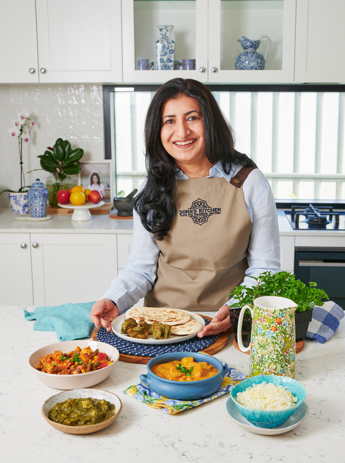 Sona at her table, presenting a spread of freshly cooked Indian dishes